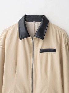 Dettaglio giacca beige con colletto in pelle PU nera e cerniera metallica