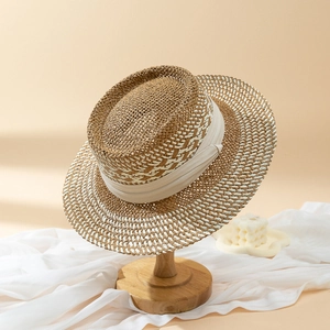Women's chic two-tone straw sun hat with beige ribbon detail on a wooden display stand