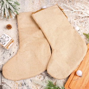 Set of two beige burlap Christmas stockings on festive winter background with pine branches