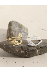 Detailed view of silver and gold branch leaf rings placed on natural dark stone