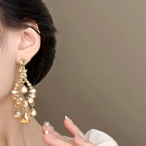 Elegant champagne gold drop fringe earrings with sparkling crystals worn by a model