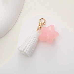Detailed view of a pink star pendant and white tassel on a gold lobster clasp keychain