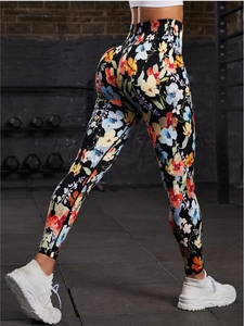 Detail of high waisted yoga leggings with vibrant floral print and bodycon fit on model