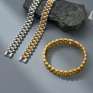 Close-up of three-link steel bracelets in silver, gold, and duo-tone finish on stones