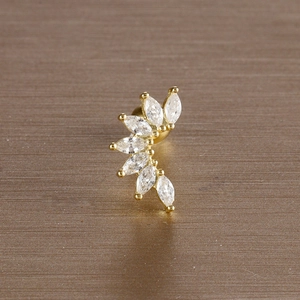 Macro shot of gold leaf tragus stud with six marquise cut zircons on a dark background