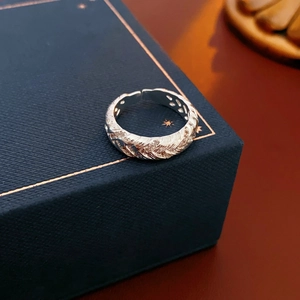 Macro detail of silver twisted band ring with sparkling zircons on blue jewelry box