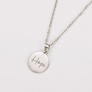 Macro detail of silver stainless steel round pendant with engraved Hope inscription