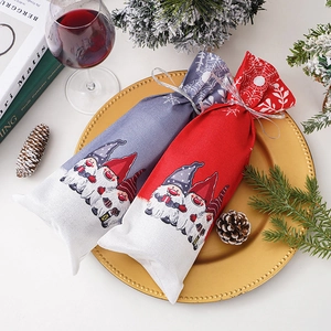 Close-up of Christmas gnome wine bottle bags in red and grey on festive dinner table