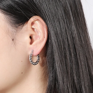 Detail showing the silver chain link hoop earring texture on model ear