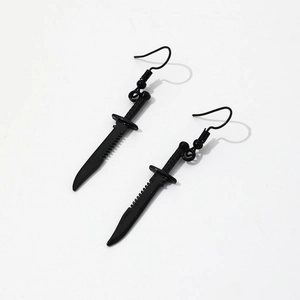 Detailed close-up of matte black dagger earrings with serrated blade and metal hooks