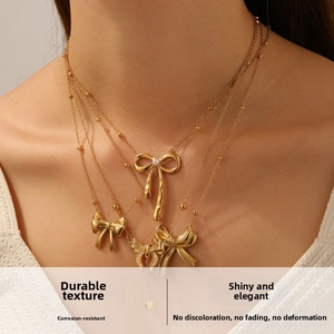 Gros plan du collier doré multicouche avec pendentifs nœuds et perles sur tricot