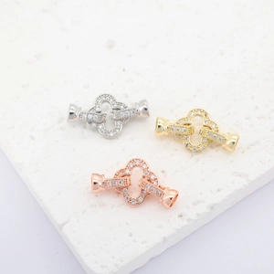Macro shot of clover-shaped jewelry clasps in gold, silver, and rose gold with pavé zircon