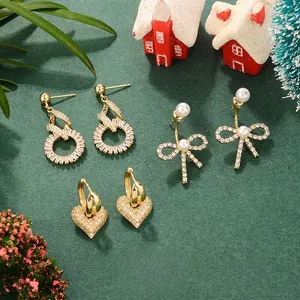 Close-up of bow and heart earrings set with zircon and pearls in festive scene