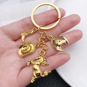 Golden Western cowboy keychain with boot, hat and horse charms held in hand