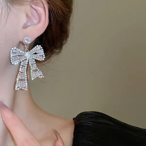 Close-up of bow knot silver earrings with inlaid trapezoid cubic zirconia on model