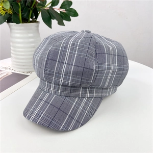 Detail of vintage grey plaid newsboy cap on white desk with elegant accessories