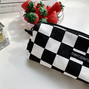 Close-up of checkerboard canvas pencil case with zipper and black fabric label detail