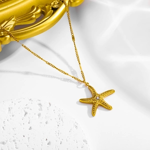 Detail of a gold starfish necklace with a sparkling diamond center on a stone tray