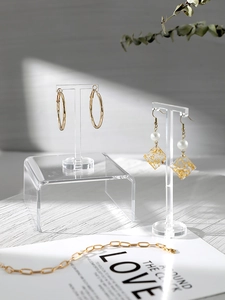 Transparent acrylic earring display stand set for jewelry photography on a wooden surface