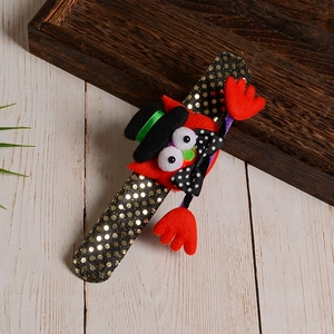 Macro detail of sequined Halloween slap bracelet with red plush character and festive decor