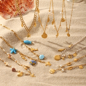 Gold ocean themed tassel necklaces with seashell and starfish pendants on beach sand
