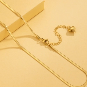 Detail of a golden stainless steel snake chain featuring an extender and heart pendant