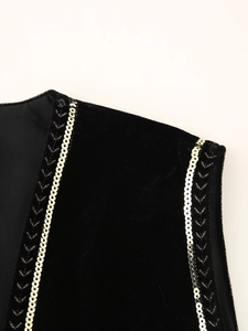 Close-up of black velvet vest shoulder with gold sequin trim and intricate embroidery