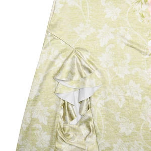 Détail du tissu à fleurs vert clair avec bord à volants sur une robe à fente haute