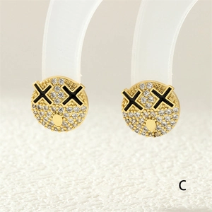 Macro view of gold-plated smiley face earring with white zircon inlay and XX eyes