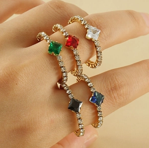 Close-up of five gold rings featuring colorful square gemstones and sparkling crystals