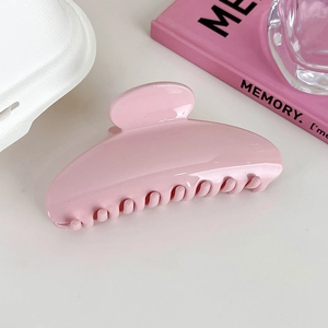Detail of a large pink acrylic hair claw clip on an aesthetic white background