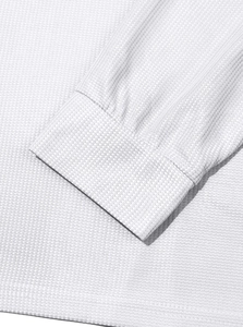 Macro shot of white waffle knit texture and ribbed cuff on a men's long sleeve shirt