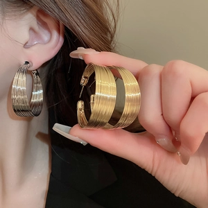 Close-up of stylish gold and silver geometric hoop earrings worn by a model