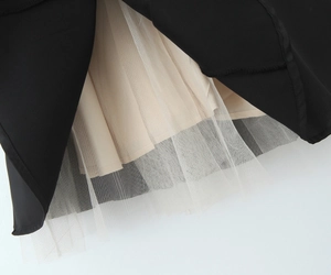 Détail montrant les couches de satin noir, doublure plissée beige et jupon en maille blanche