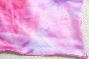 Detail of pink and purple tie-dye knit fabric showing texture and stitching quality