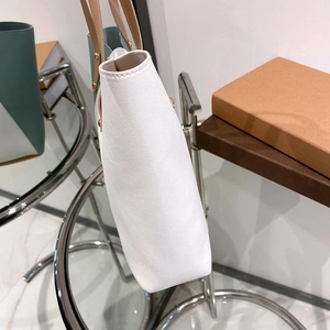 Minimalist white leather tote bag with brown handles shown from a side profile view