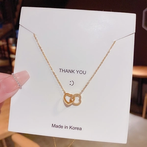 Detailed view of intertwined gold double heart pendant on a Thank You display card