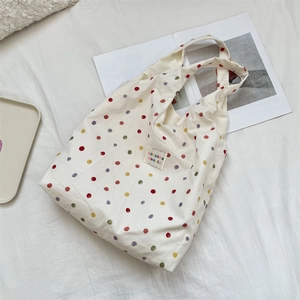 Détail du sac cabas en toile à pois colorés avec étiquette de marque carrée tissée