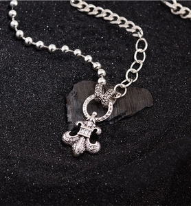 Detail of 925 sterling silver fleur-de-lis pendant with zircon on a Cuban link chain