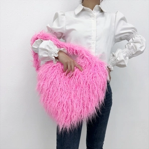 Close-up of fluffy pink heart-shaped faux fur crossbody bag worn by a model