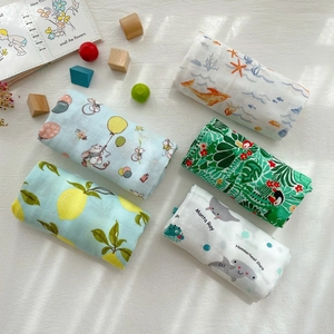Detailed flat lay of five rolled muslin bamboo cotton baby blankets with diverse animal prints