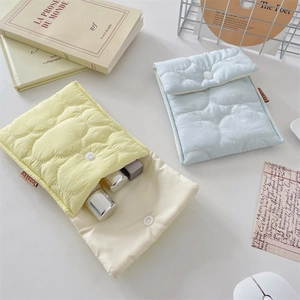 Quilted cotton sanitary pouch in yellow and blue colors with button closure on desk