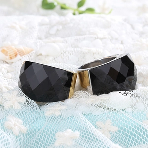 Detail of wide metal rings featuring large faceted black stones on white lace background
