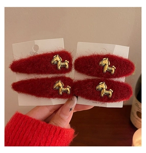 Dettaglio di fermagli per capelli in peluche rosso con ciondoli a cavallo dorati