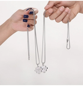 Close-up of silver puzzle couple necklaces with Weirdo 1 and Weirdo 2 engravings