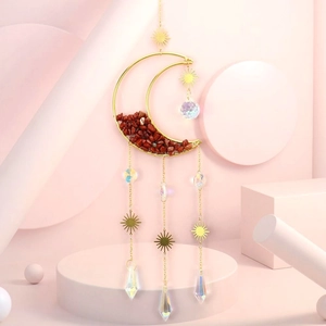 Detail of golden moon suncatcher with red natural stones and multi-faceted crystal prisms