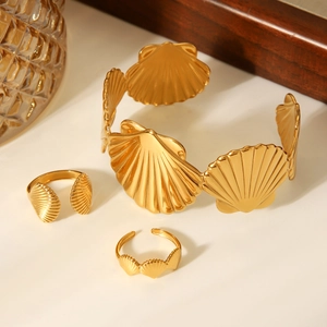 Detailed close-up of a gold shell-shaped bangle and ring set on an elegant surface