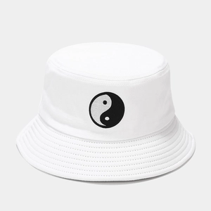 Gros plan sur la broderie Yin-Yang d'un bob en coton blanc avec bordure surpiquée