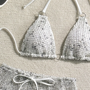 Close-up of white crochet three-piece bikini with mesh texture and silver metal ring detail