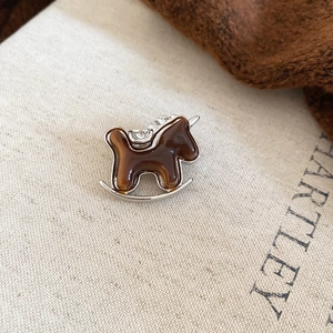 Detail of a vintage rocking horse brooch with amber resin, silver metal, and small crystals